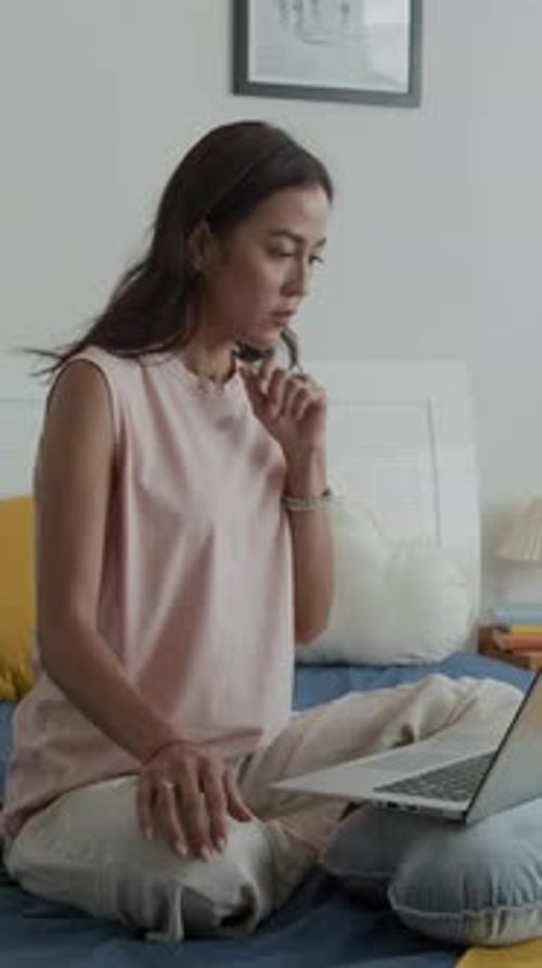 Woman Working on Laptop Sitting on Bed