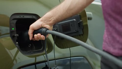Close Up of Driver Attaching Electric Cable to EV Vehicle Charging Port