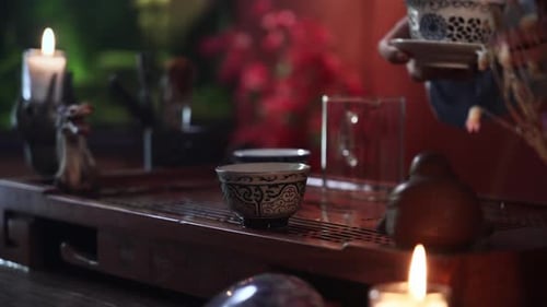 Hands Pouring Tea into Glass Cup at Table