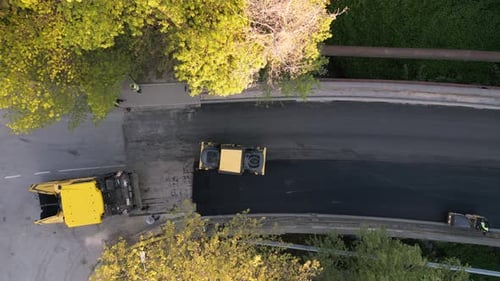 Luftaufnahme des Baus einer neuen Straße, als Asphaltpflaster, Walzen, Maschinen und Arbeiter kommen