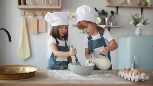 Zwei Kinder in weißer Kochuniform, die Mehl mischen und Milch in die Küche geben