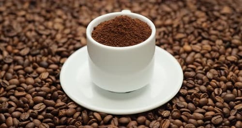 Cup Full of Ground Coffee on Coffee Beans