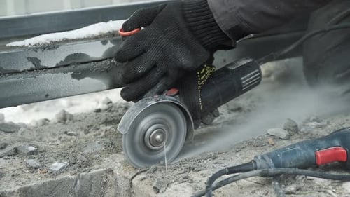 Worker cutting metal tube using an Angle Grinder. Bright sparks and flashes