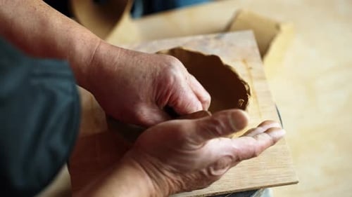 Over Shoulder View of Hands Shaping Clay Bowl in Pottery Workshop