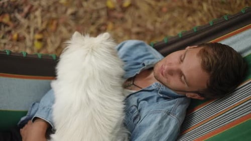 Man Resting in Hammock With Adorable Dog