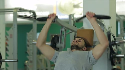 Bearded man doing weight lifting in gym