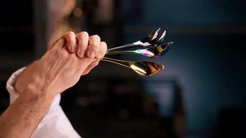 Chef's Hands Holding Golden and Iridescent Spoons for Culinary Design