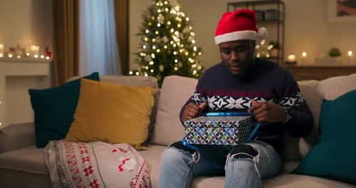 Young Adult Opens a Christmas Present at Home