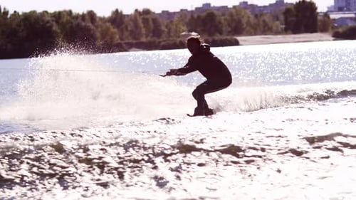 Wakeboarder jumps high performing stunts on city river wakeboarding training