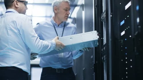 Zwei Servertechniker installieren Hardware im Server-Rack. Sie arbeiten in einem großen modernen Rechenzentrum.