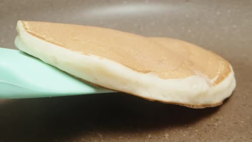 transfer the finished pancake from the frying pan to a plate with a spatula. extreme close-up.