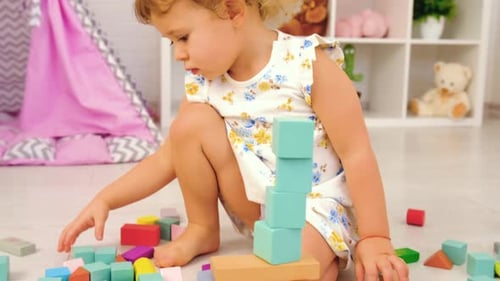 Cute Child Plays with Colorful Building Blocks at Home