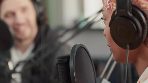 Podcast Host Speaking into Microphone Talking to Guest in Studio