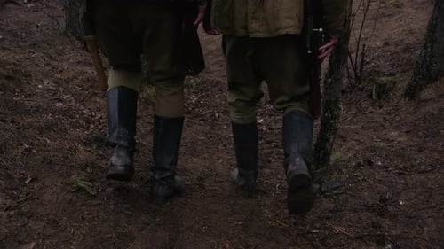 Zwei Soldaten des Zweiten Weltkriegs gehen mit Gewehren, Helmen und Stiefeln durch einen Wald