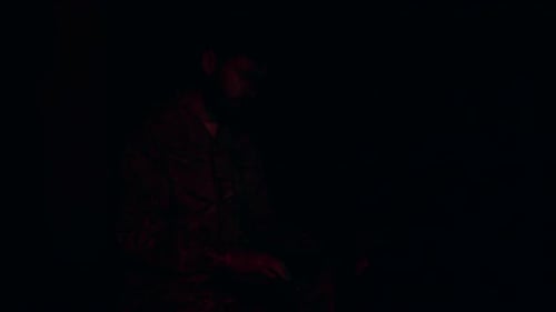 In a Greenlit Server Room a Soldier Intently Works on a Laptop
