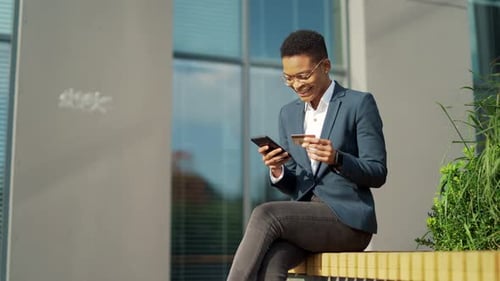 African American business woman shopping or making payment using mobile phone smartphone and credit
