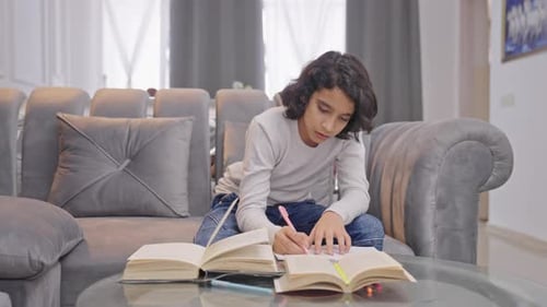 Focused Child Studying at Home With Books