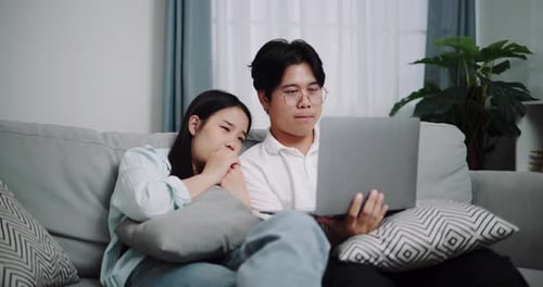 Couple Relaxing on Couch with Laptop Computer Indoors