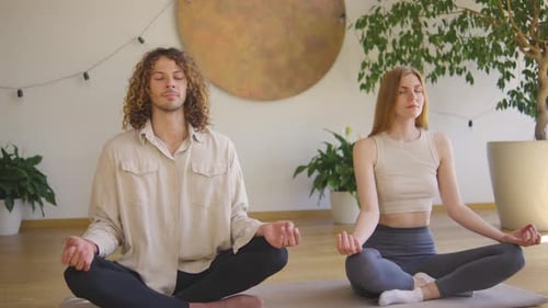 Couple Practicing Yoga and Meditation Indoors During Daytime