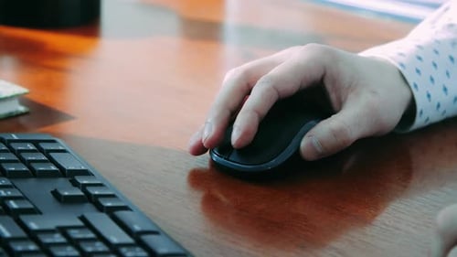 Hand using computer mouse on wood desk