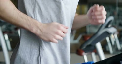 A guy in the gym to stay fit and have defined muscles or lose weight runs on the treadmill with a