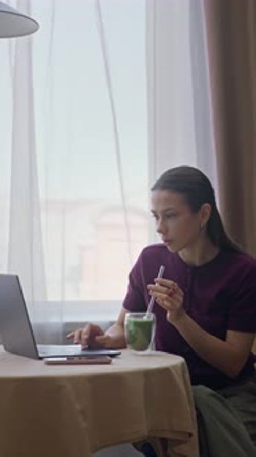 Woman Working on Laptop While Drinking Beverage