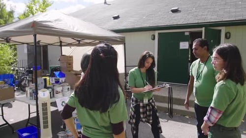 Volunteers With Clipboard Meeting In Sunny Parking Lot