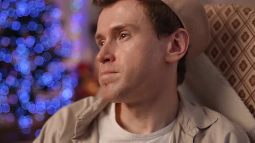Man Sitting Pensively Near Christmas Tree