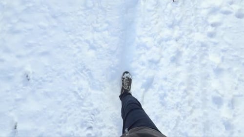 Human man legs walking on winter snowy path. Top view with slow motion