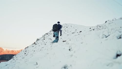 Young man hiking uphill on a snow-covered mountain in Hoddevik, Norway.