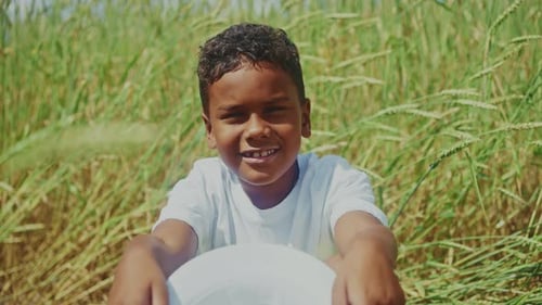 Young Boy Smiling While Sitting in a Golden Wheat Field on a Sunny Day