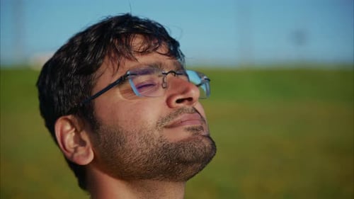 Man Enjoying Fresh Air with Closed Eyes in a Green Field