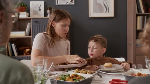 Woman Serving Child Food at Family Meal