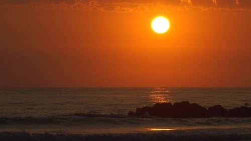 Peaceful mediterranean sea sunrise reflecting on ocean waves breaking on rocks
