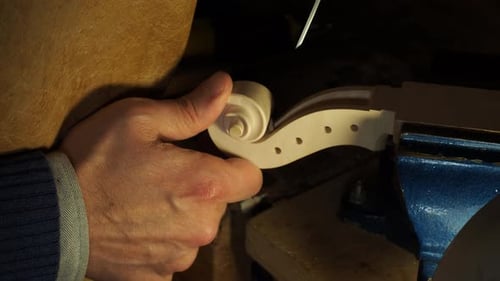 Traditional Cremonese school luthier refining the volute and peg box on a new violin scroll.