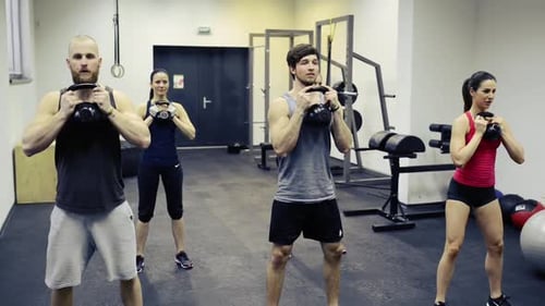 Young People in Crossfit Gym Doing Squats with Kettlebells Active
