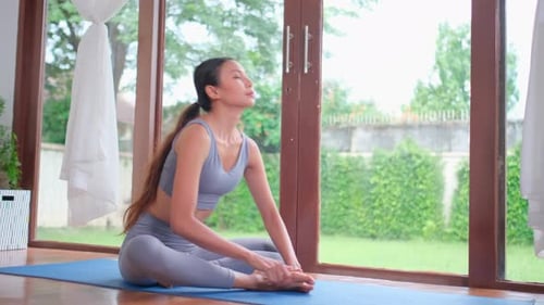 Side view of professional Asian woman bent body down flat on the ground for training yoga at home