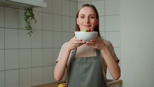 Woman Holds Bowl with Salad in Kitchen