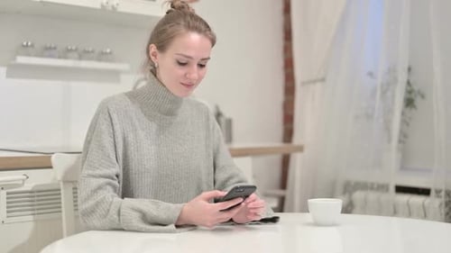Woman Using Phone at Home at Table