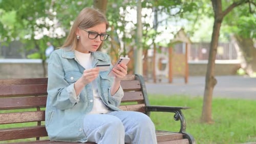 Woman on Bench Using Credit Card and Phone