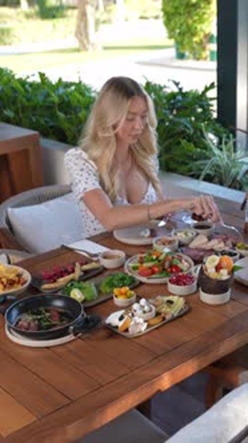 Femme profitant d'un somptueux petit-déjeuner en plein air composé de fruits frais, de viandes et de légumes