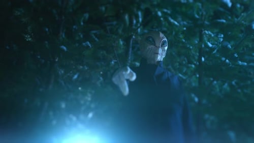 Un extraterrestre debout dans une forêt sombre et utilisant une superpuissance