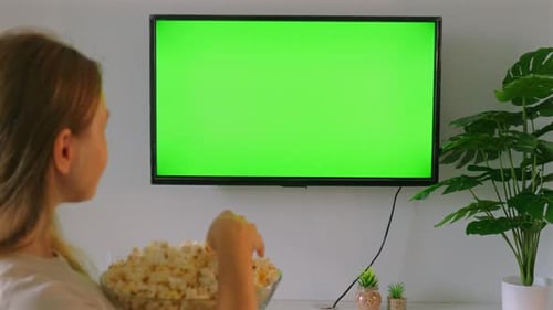Young Woman Eating Popcorn While Watching Television with Green Screen