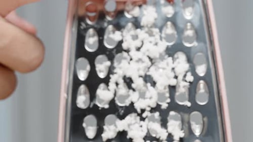 Scraping Fine Coconut Shavings Grated on a Grater with a Finger. Close-Up, Slow Motion.