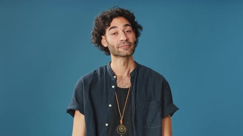 Happy man showing ok gesture looking at camera isolated on blue background in studio