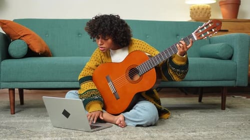 Teen Plays Guitar with Laptop Indoors