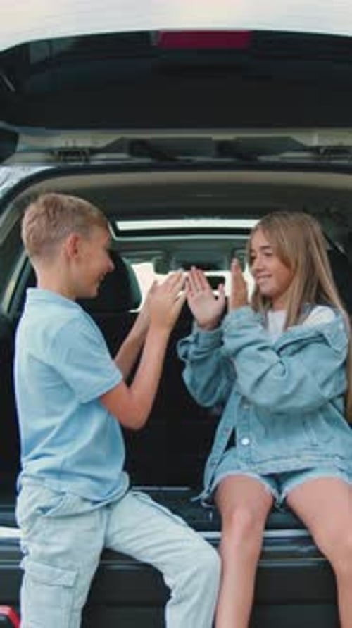Cute Cheerful Playful 1012Yearold Brother and Sister Gaming in Auto Trunk During Stop on Green