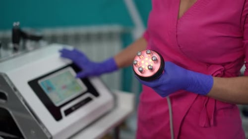 Female Cosmetologist Holding LED Vacuum Massage Device in Beauty Clinic