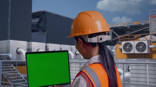 Back View Of Asian Female Engineer Working On A Green Screen Laptop On Rooftop HVAC