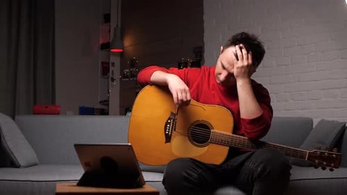 Upset Man with a Guitar Grabbed His Head with His Hands
